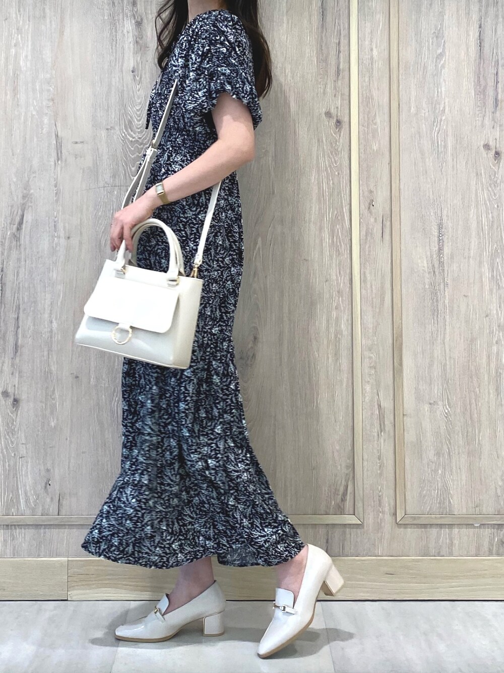 ホワイト系のローファー、ブラック系のワンピース、ホワイト系のハンドバッグを着用したレディースの冬コーディネートの2枚目の写真