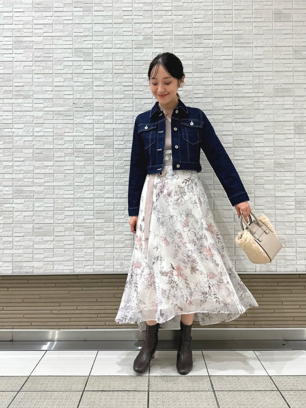 ブラウン系のブーツ、ホワイト系のハンドバッグ、ブルー系のデニムジャケットを着用したレディースの夏コーディネートの3枚目の写真