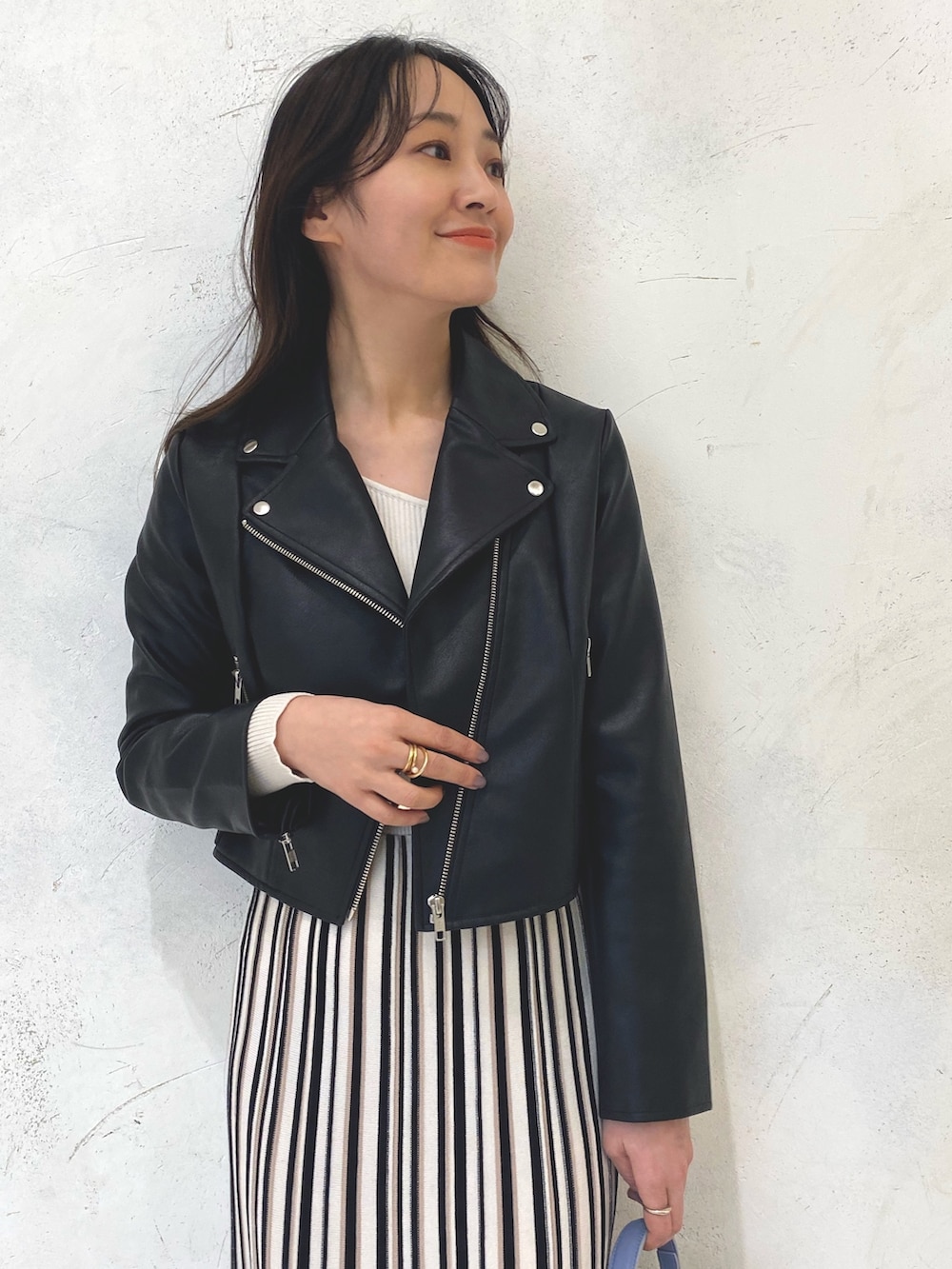 ブルー系のハンドバッグ、ブラック系のライダースジャケット、ホワイト系のワンピースを着用したレディースの冬コーディネートの4枚目の写真