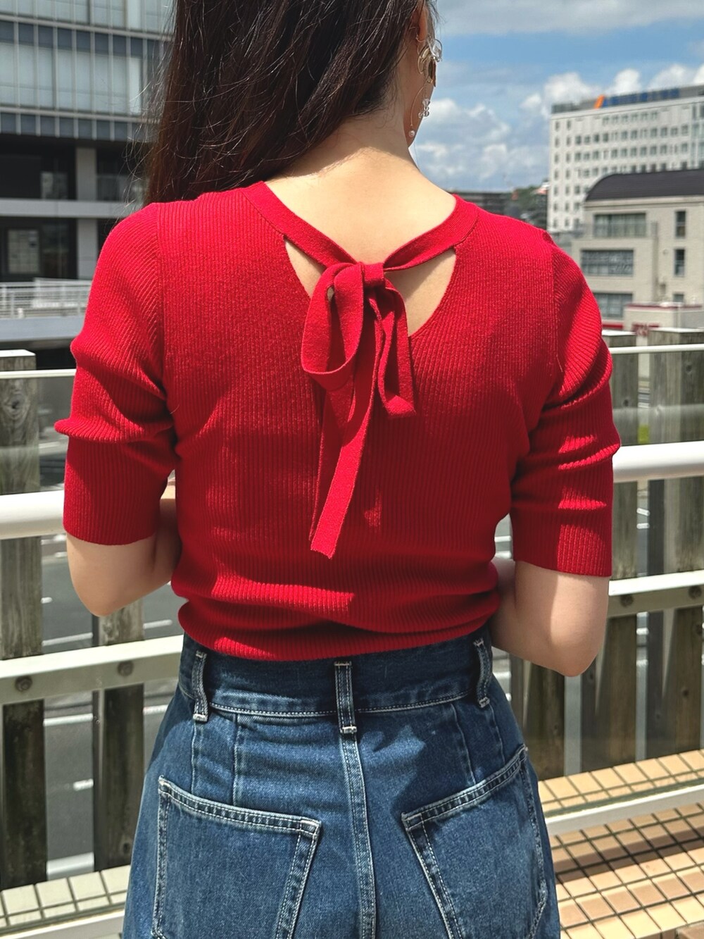 レッド系のニット/セーター、ブルー系のデニムパンツ、ブラウン系のブーツを着用したレディースの夏コーディネートの7枚目の写真