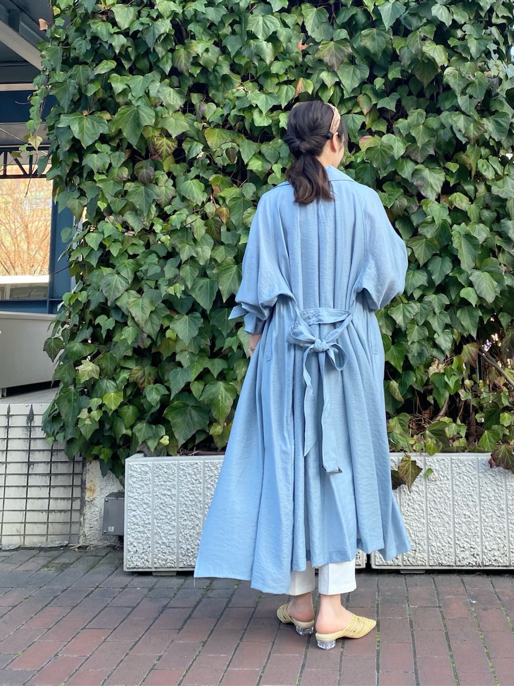 ブルー系のトレンチコート、イエロー系のサンダル、ホワイト系のその他パンツを着用したレディースの春コーディネートの6枚目の写真