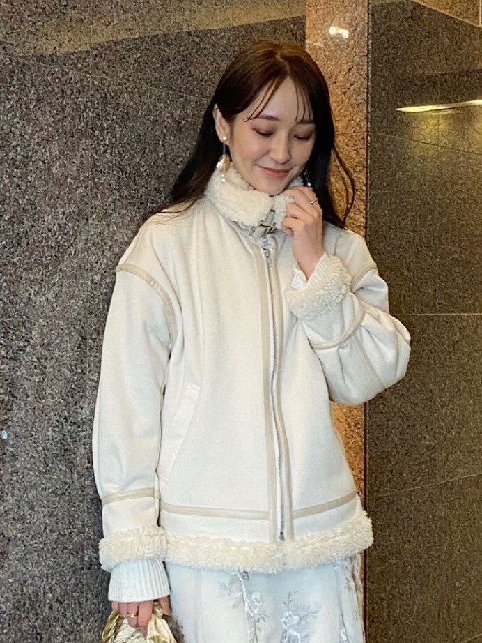 ベージュ系のクラッチバッグ、ホワイト系のムートンコート、ホワイト系のニット/セーターを着用したレディースの秋コーディネートの3枚目の写真