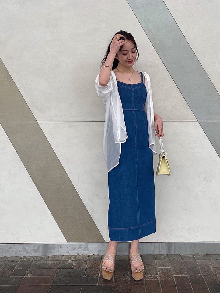 イエロー系のショルダーバッグ、ブルー系のジャンパースカート、ベージュ系のキャミソールを着用したレディースの春コーディネートの2枚目の写真