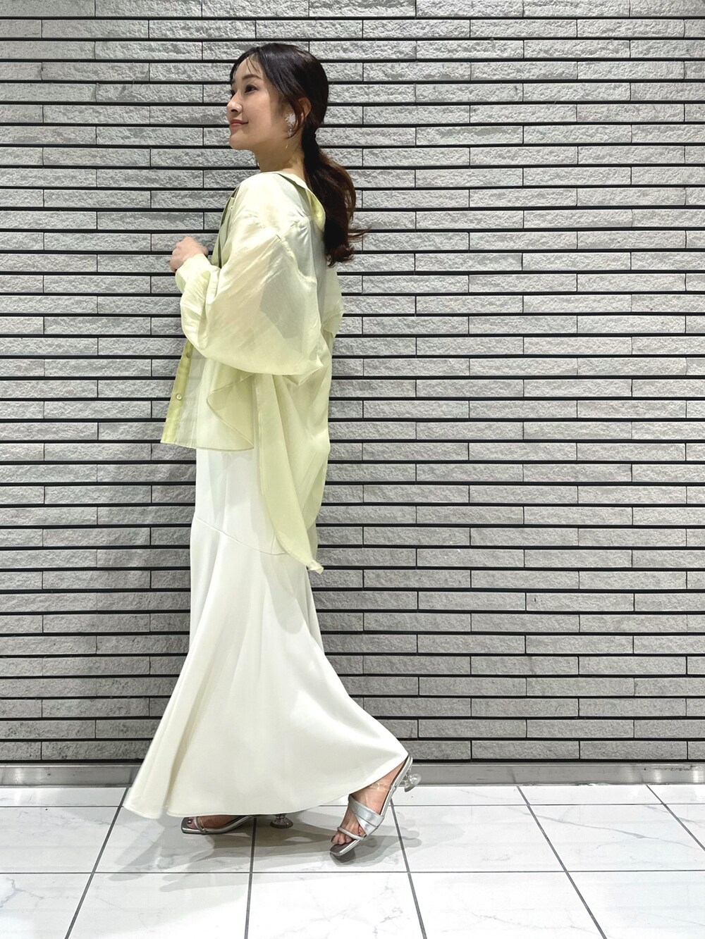 シルバー系のサンダル、ホワイト系のスカート、グレー系のニット/セーターを着用したレディースの春コーディネートの3枚目の写真