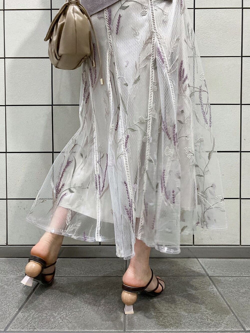 ベージュ系のクラッチバッグ、ブラウン系のサンダル、ホワイト系のスカートを着用したレディースの夏コーディネートの7枚目の写真