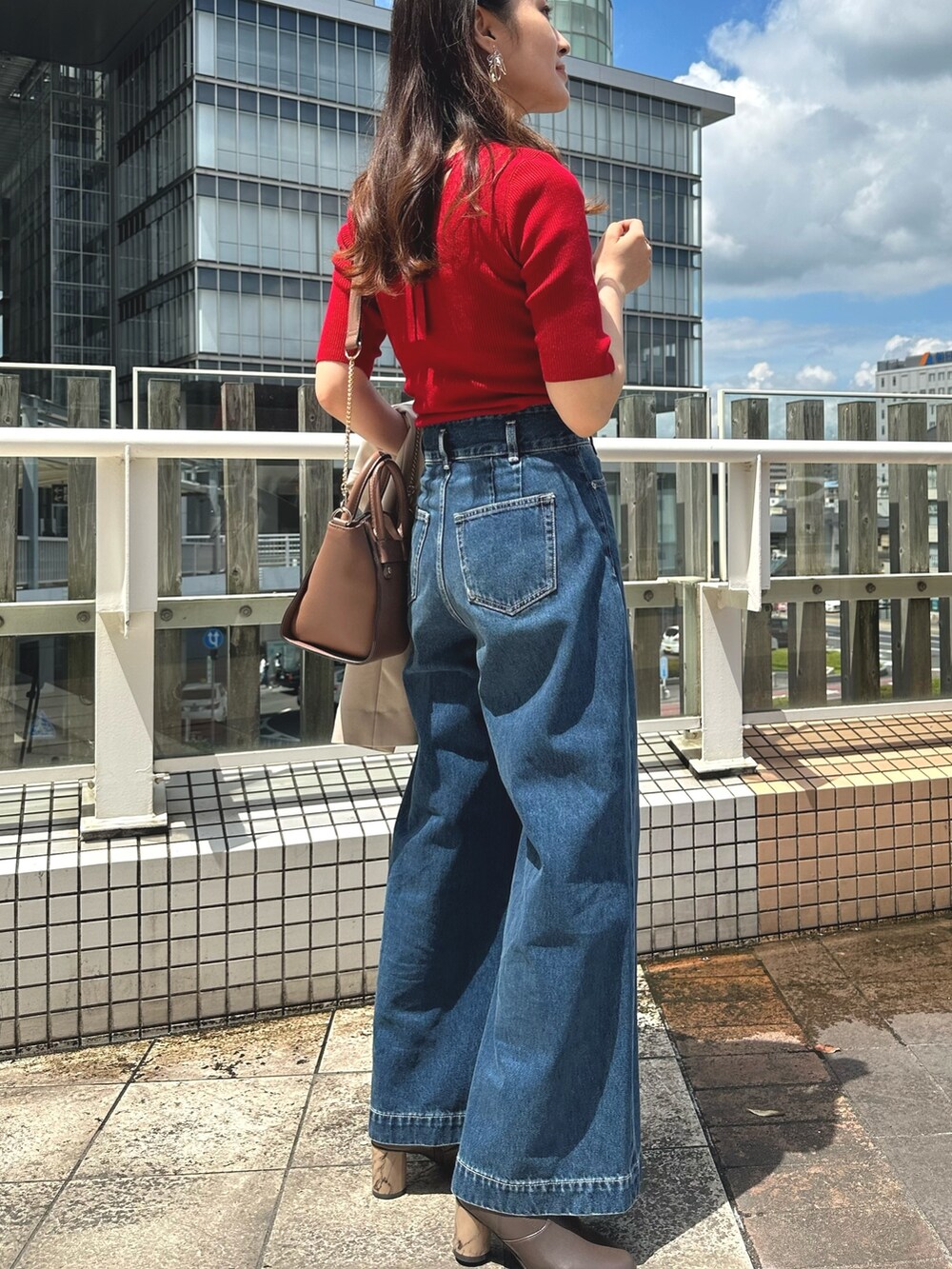 レッド系のニット/セーター、ブルー系のデニムパンツ、ブラウン系のブーツを着用したレディースの夏コーディネートの3枚目の写真