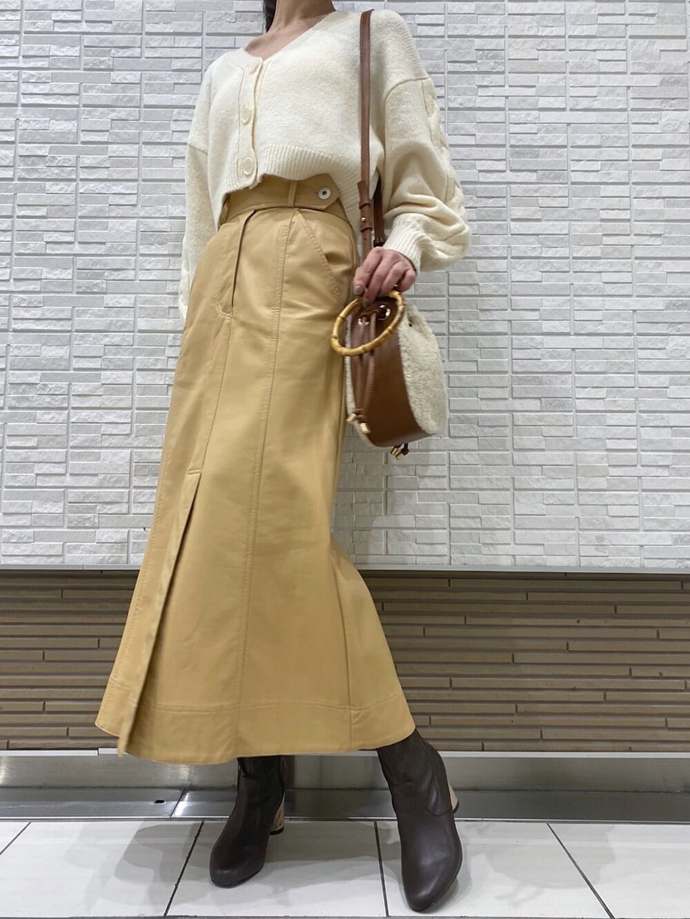 ベージュ系のスカート、ブラウン系のブルゾン、ブラウン系のハンドバッグを着用したレディースの冬コーディネートの6枚目の写真