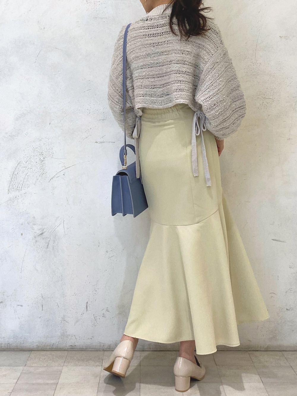 ホワイト系のローファー、イエロー系のスカート、ブルー系のハンドバッグを着用したレディースの冬コーディネートの4枚目の写真