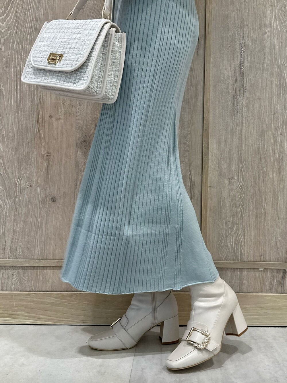 ホワイト系のハンドバッグ、ホワイト系のブーツ、ブルー系のワンピースを着用したレディースの冬コーディネートの7枚目の写真