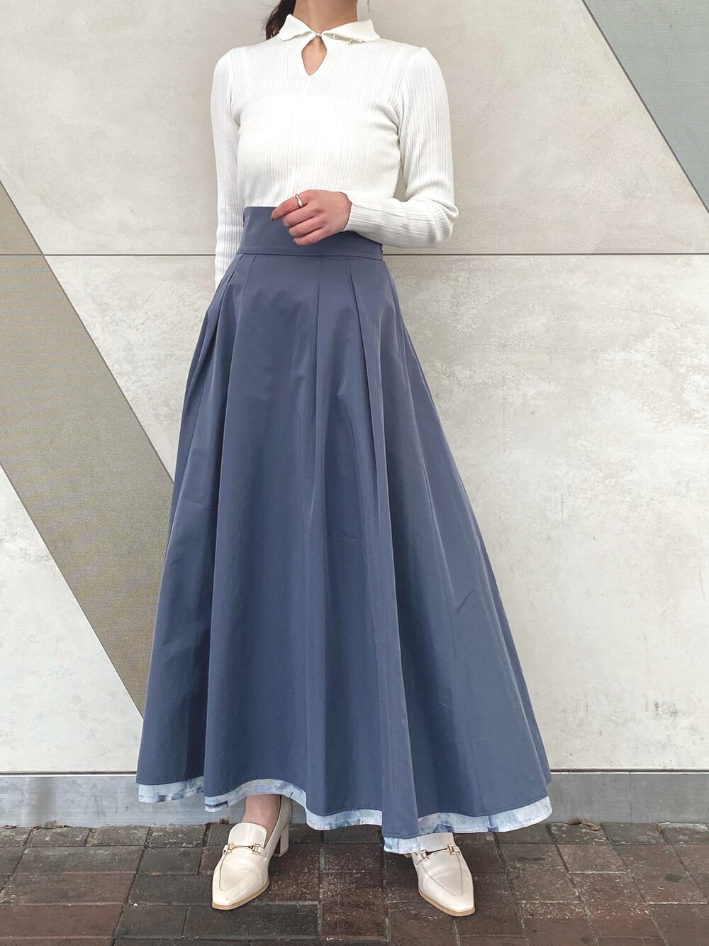 ブルー系のスカート、ホワイト系のニット/セーター、ホワイト系のキャミソールを着用したレディースの冬コーディネートの2枚目の写真