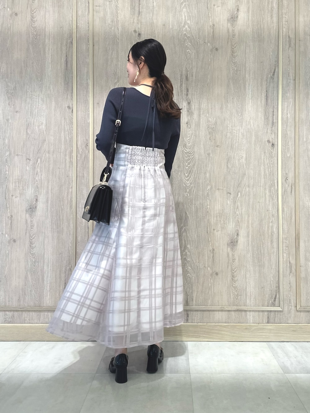 レッド系のハンドバッグ、ブラウン系のパンプス、グレー系のワンピースを着用したレディースの秋コーディネートの4枚目の写真