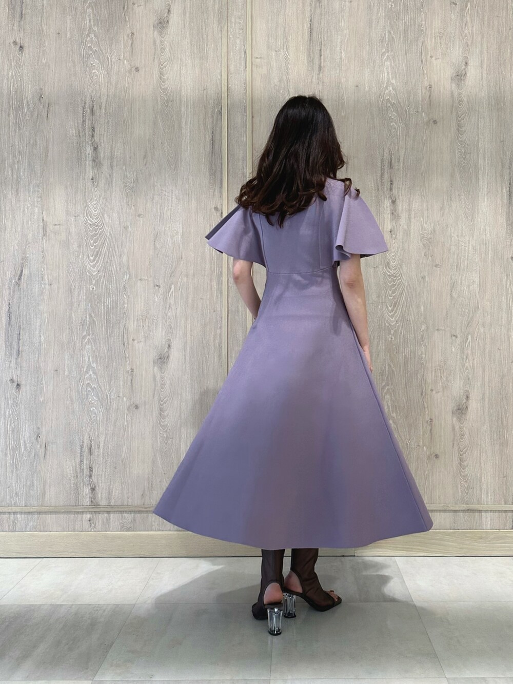 ブラウン系のハンドバッグ、ブラウン系のブーツ、パープル系のワンピースを着用したレディースの春コーディネートの4枚目の写真