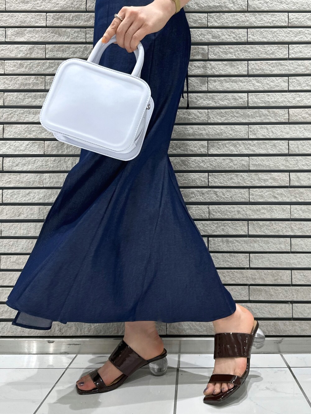ブルー系のハンドバッグ、ブルー系のスカート、ブルー系のシャツ/ブラウスを着用したレディースの夏コーディネートの9枚目の写真