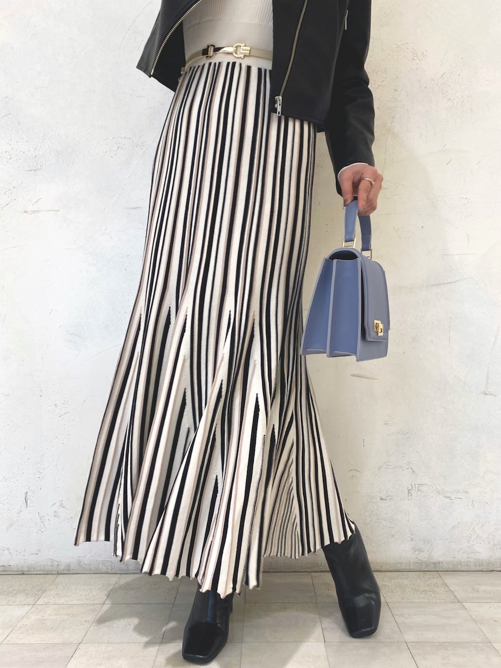 ブルー系のハンドバッグ、ブラック系のライダースジャケット、ホワイト系のワンピースを着用したレディースの冬コーディネートの6枚目の写真