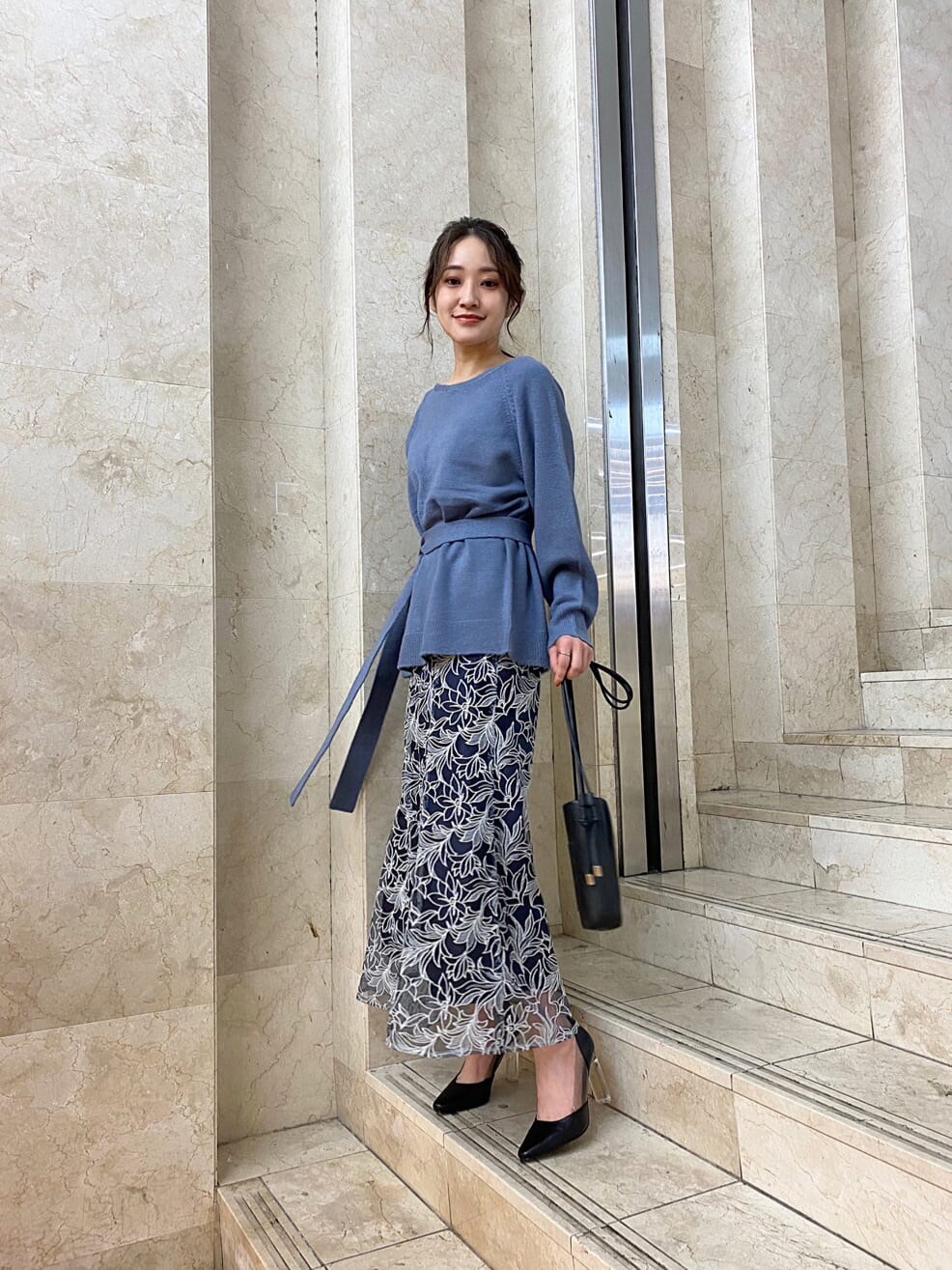 ピンク系のチェスターコート、ブラック系のパンプス、ブラック系のハンドバッグを着用したレディースの秋コーディネートの3枚目の写真