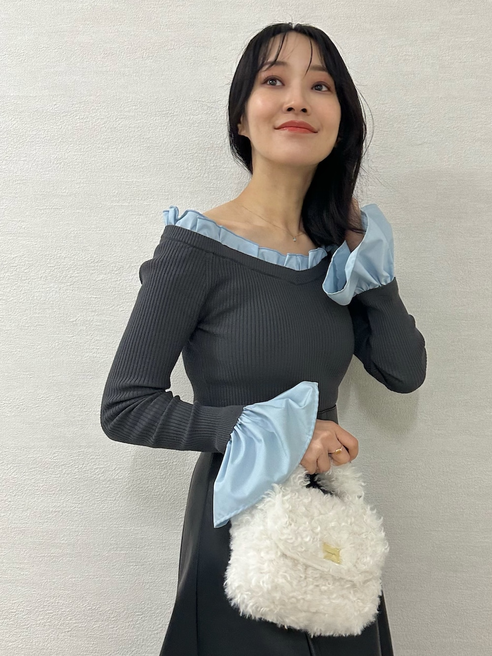 ホワイト系のハンドバッグ、グレー系のブーツ、グレー系のニット/セーターを着用したレディースの冬コーディネートの6枚目の写真
