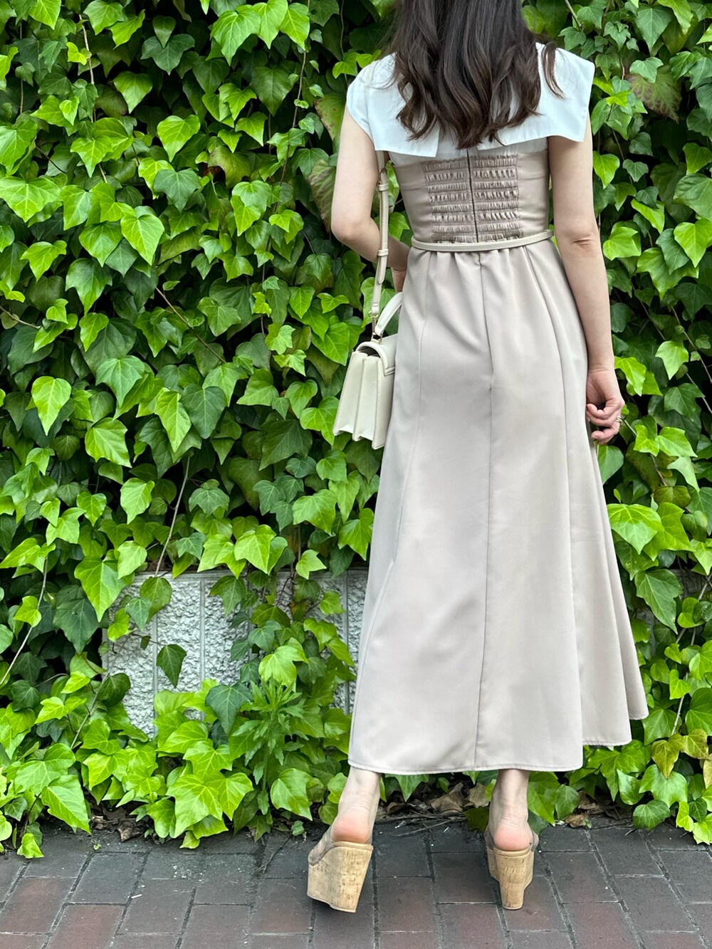 その他のサンダル、ホワイト系のハンドバッグ、ベージュ系のワンピースを着用したレディースの春コーディネートの3枚目の写真