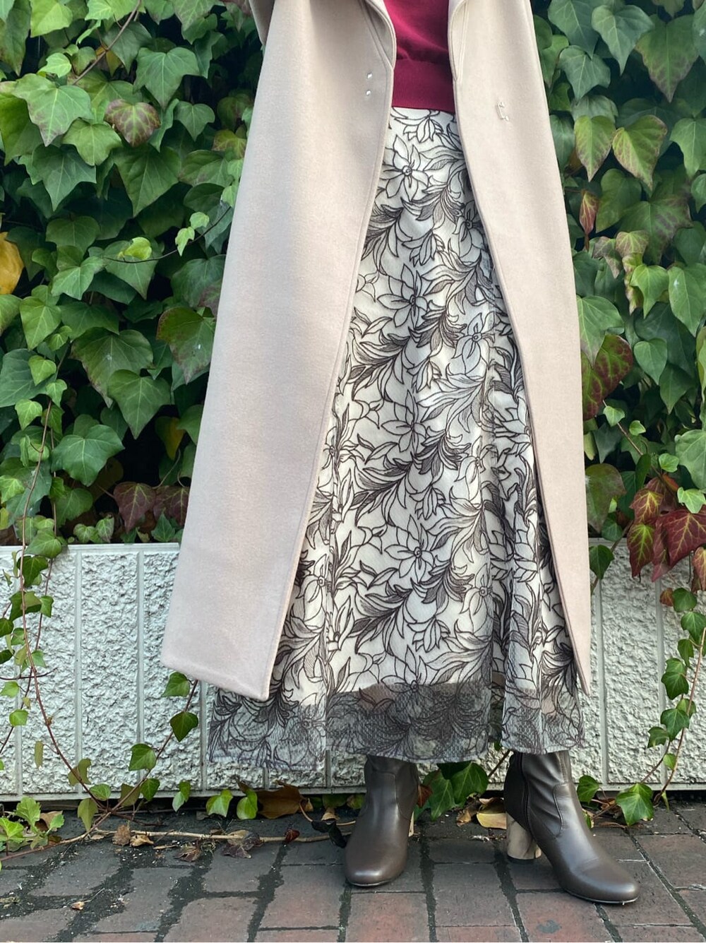 ブラウン系のその他シューズ、ベージュ系のステンカラーコート、レッド系のニット/セーターを着用したレディースの冬コーディネートの8枚目の写真