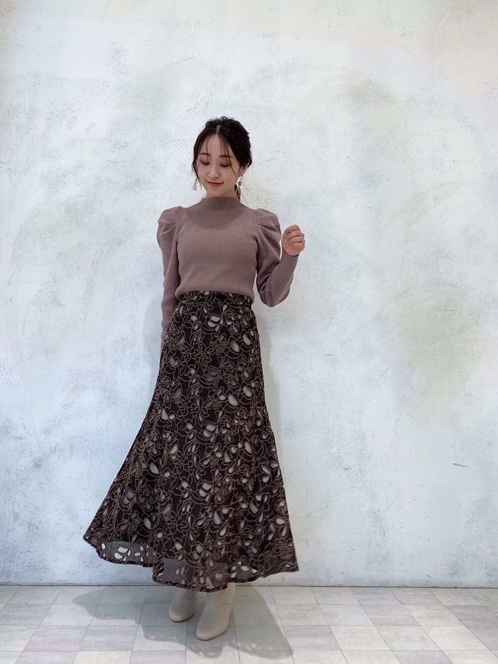 ベージュ系のその他シューズ、ブラウン系のニット/セーター、ブラウン系のスカートを着用したレディースの冬コーディネートの2枚目の写真