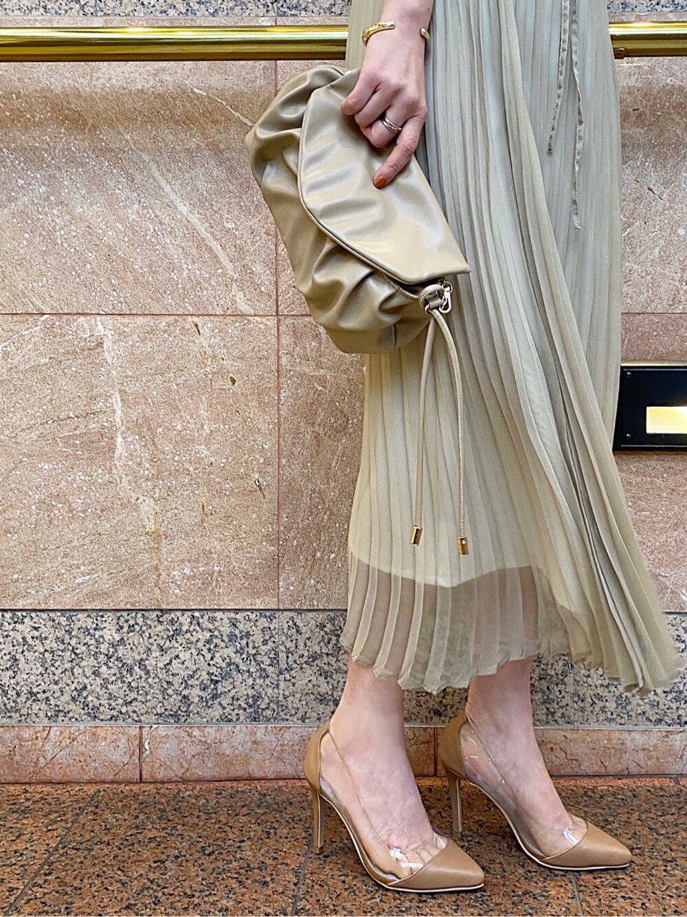 グリーン系のワンピース、ベージュ系のパンプス、ベージュ系のクラッチバッグを着用したレディースの春コーディネートの2枚目の写真