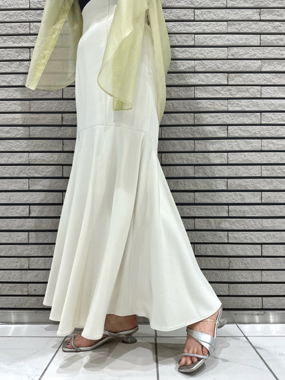 シルバー系のサンダル、ホワイト系のスカート、グレー系のニット/セーターを着用したレディースの春コーディネートの9枚目の写真