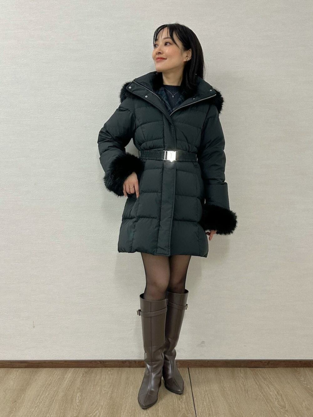 グリーン系のワンピース、ブラウン系のブーツ、ブラック系のダウンジャケット/コートを着用したレディースの冬コーディネートの7枚目の写真