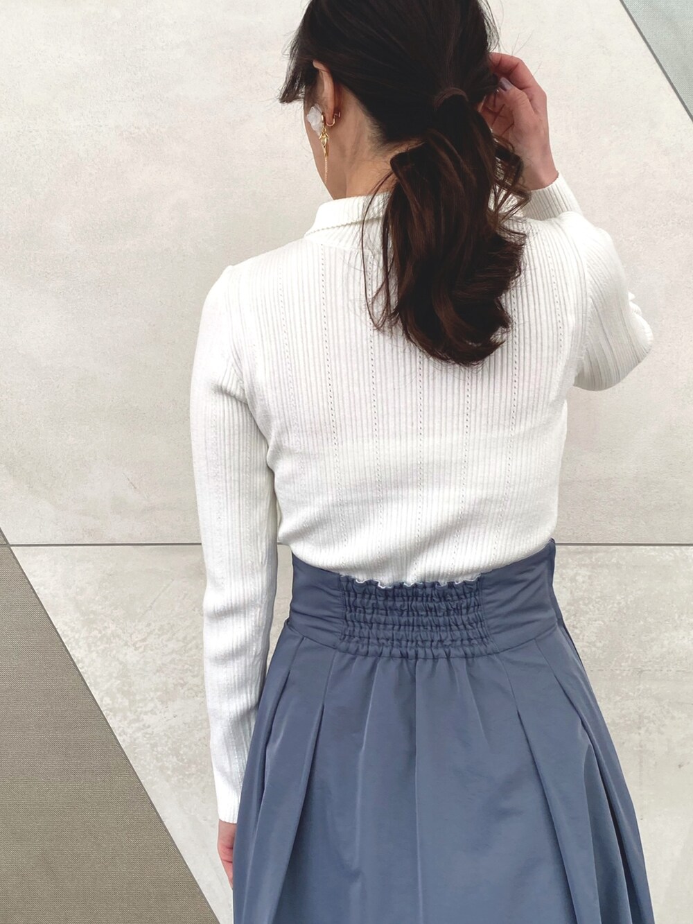 ブルー系のスカート、ホワイト系のニット/セーター、ホワイト系のキャミソールを着用したレディースの冬コーディネートの8枚目の写真