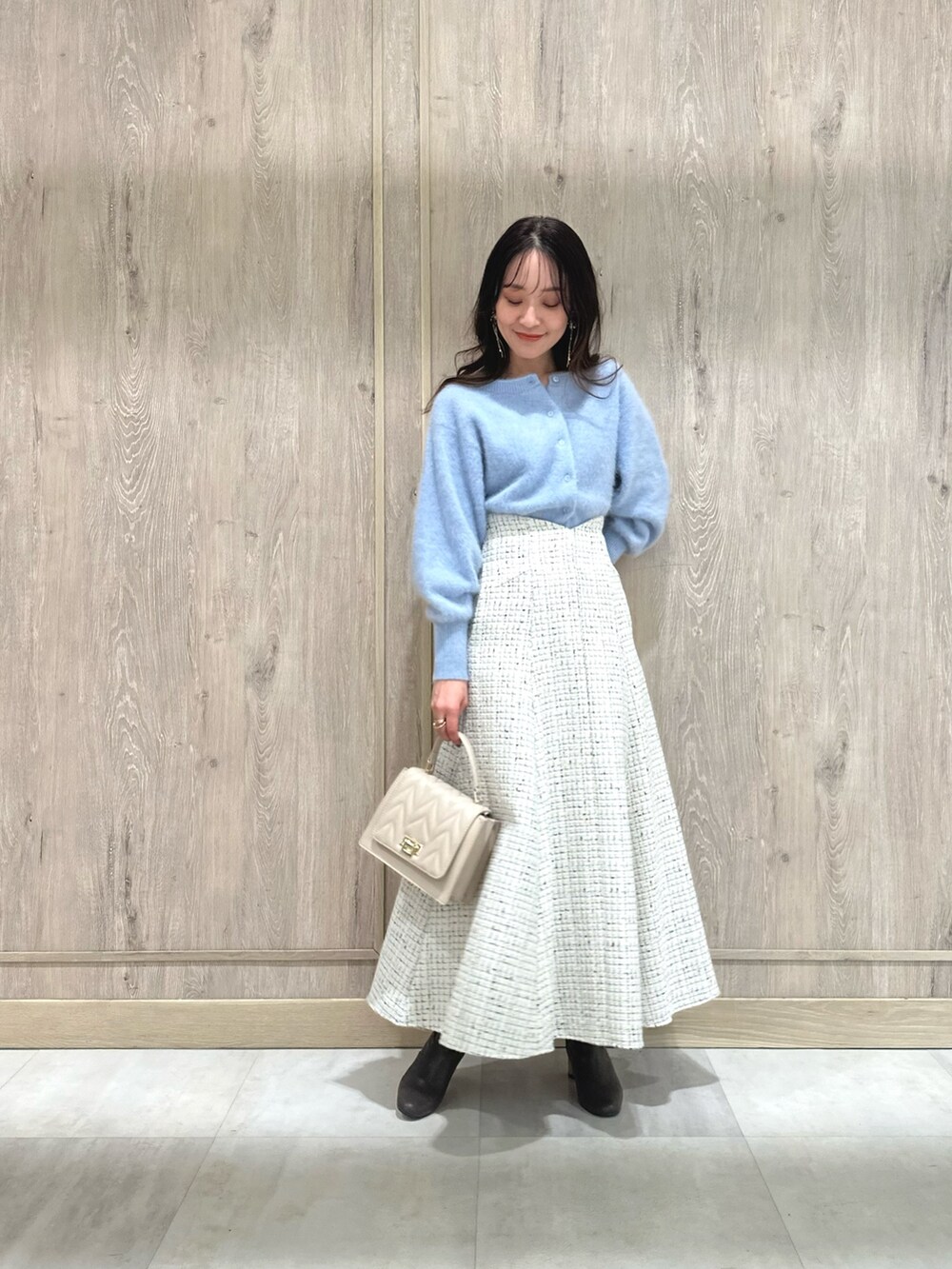 ホワイト系のスカート、ブルー系のカーディガン/ボレロ、ブラウン系のブーツを着用したレディースの秋コーディネートの2枚目の写真