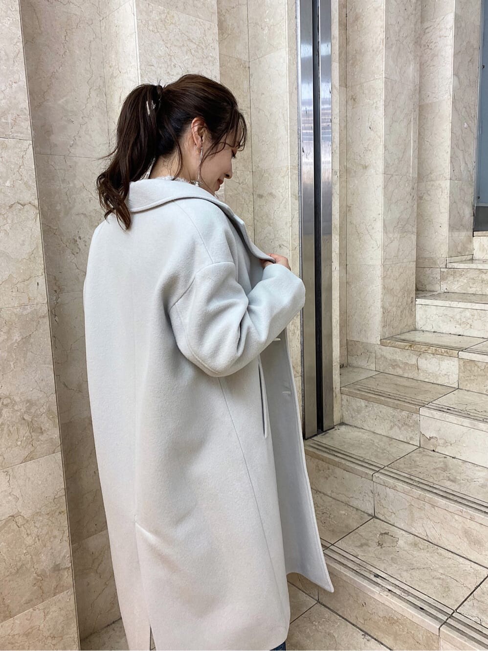 グリーン系のチェスターコート、ブルー系のスカート、ブラック系のその他シューズを着用したレディースの秋コーディネートの4枚目の写真