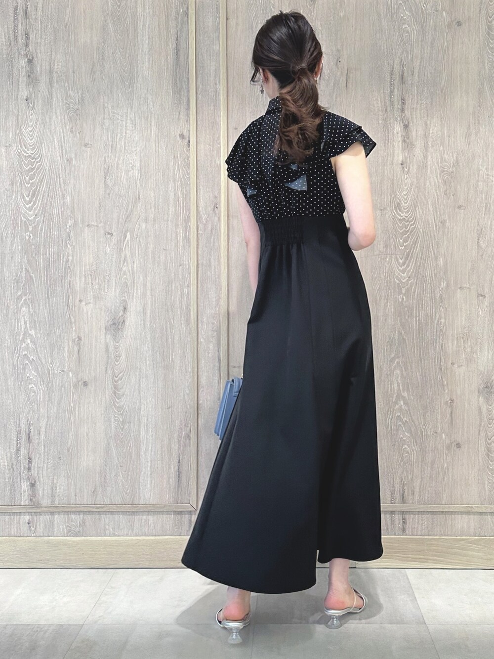 ブラック系のワンピース、ブルー系のハンドバッグ、シルバー系のサンダルを着用したレディースの春コーディネートの7枚目の写真