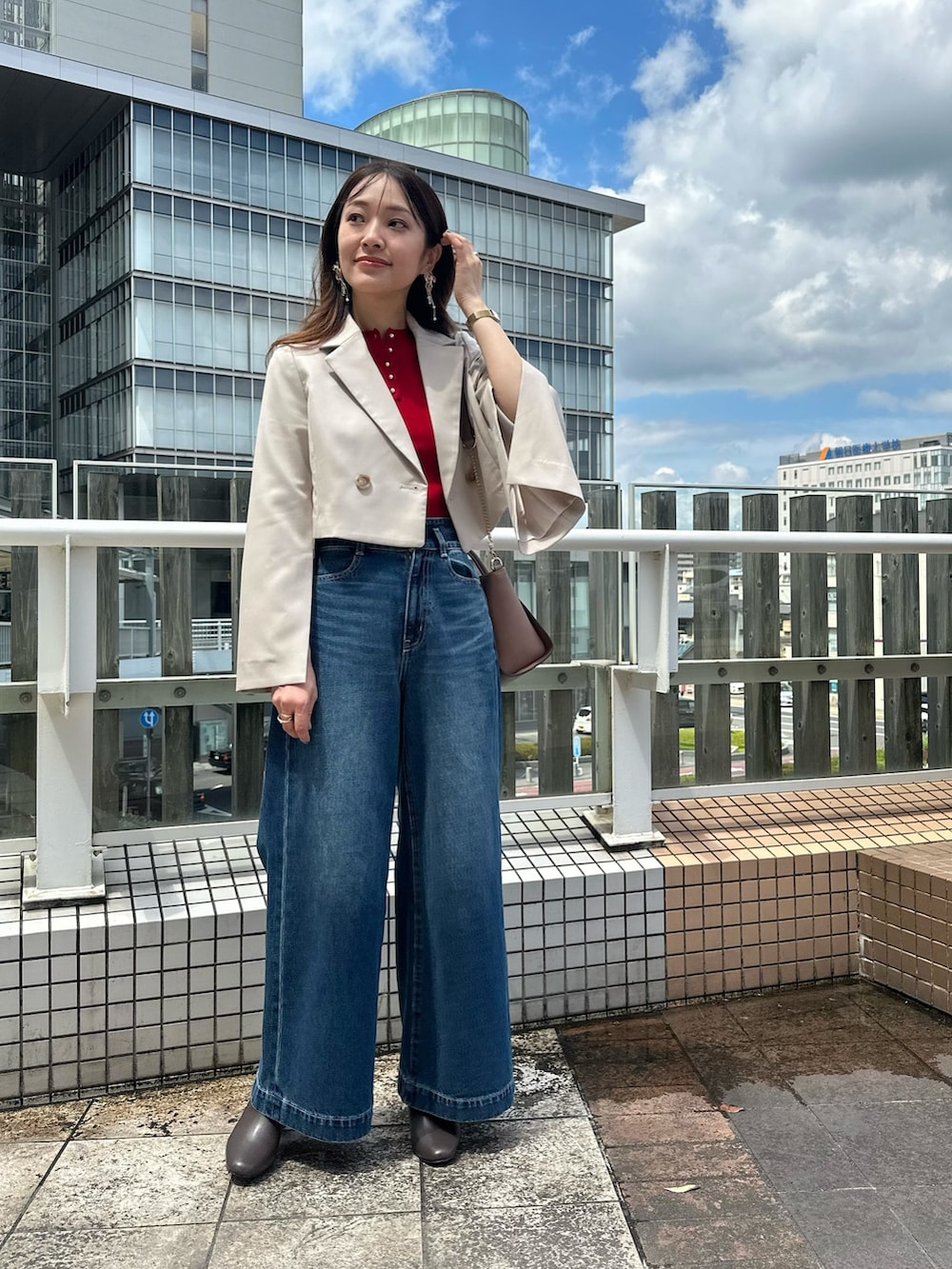 ブルー系のデニムパンツ、ブラウン系のブーツ、ブラウン系のハンドバッグを着用したレディースの夏コーディネートの2枚目の写真