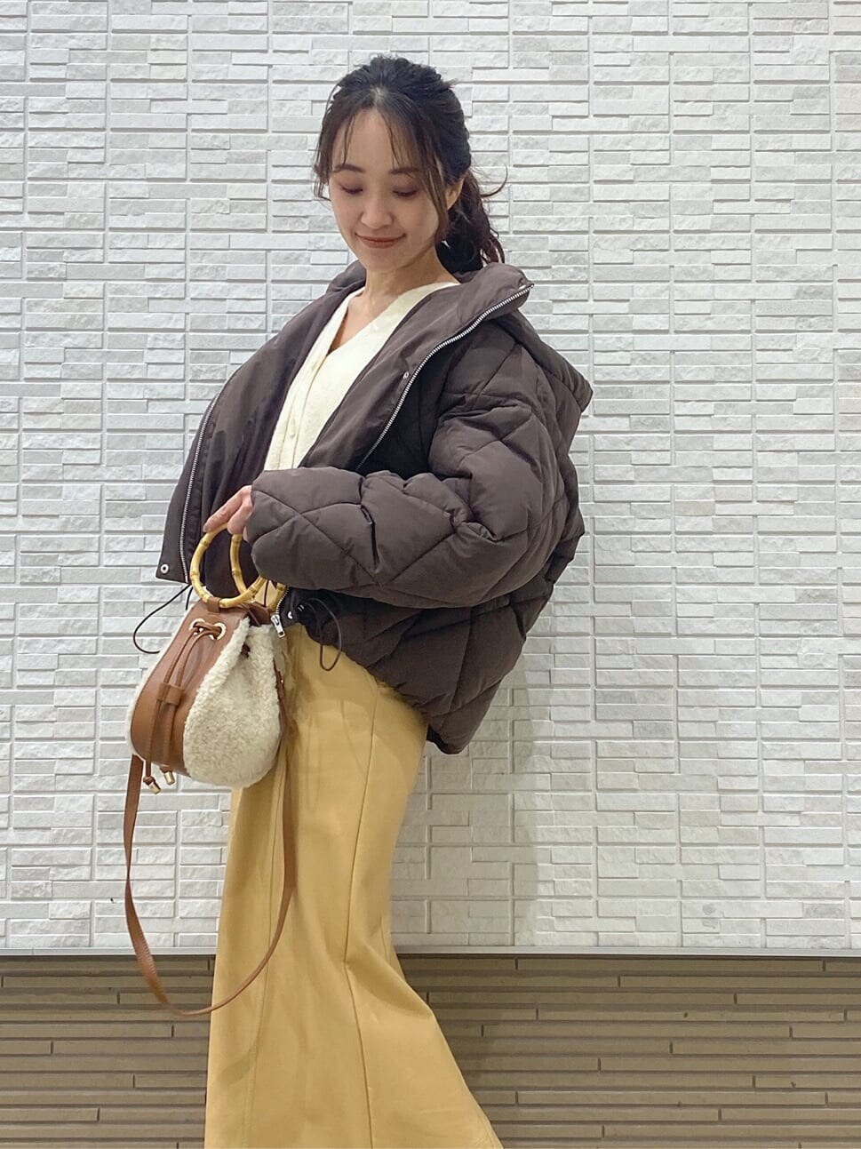 ベージュ系のスカート、ブラウン系のブルゾン、ブラウン系のハンドバッグを着用したレディースの冬コーディネートの2枚目の写真