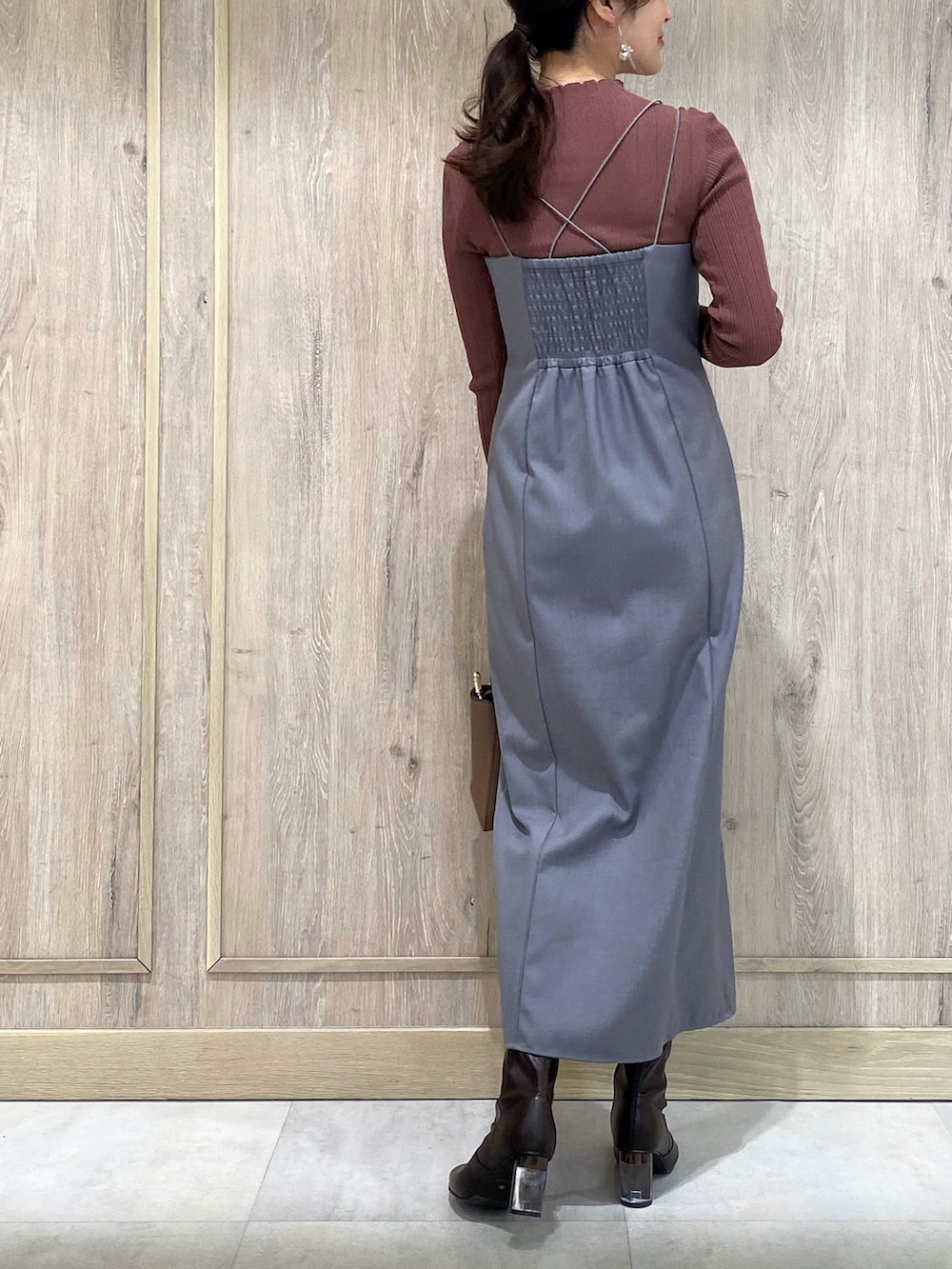グレー系のワンピース、ブラウン系のハンドバッグ、ブラウン系のブーツを着用したレディースの冬コーディネートの4枚目の写真