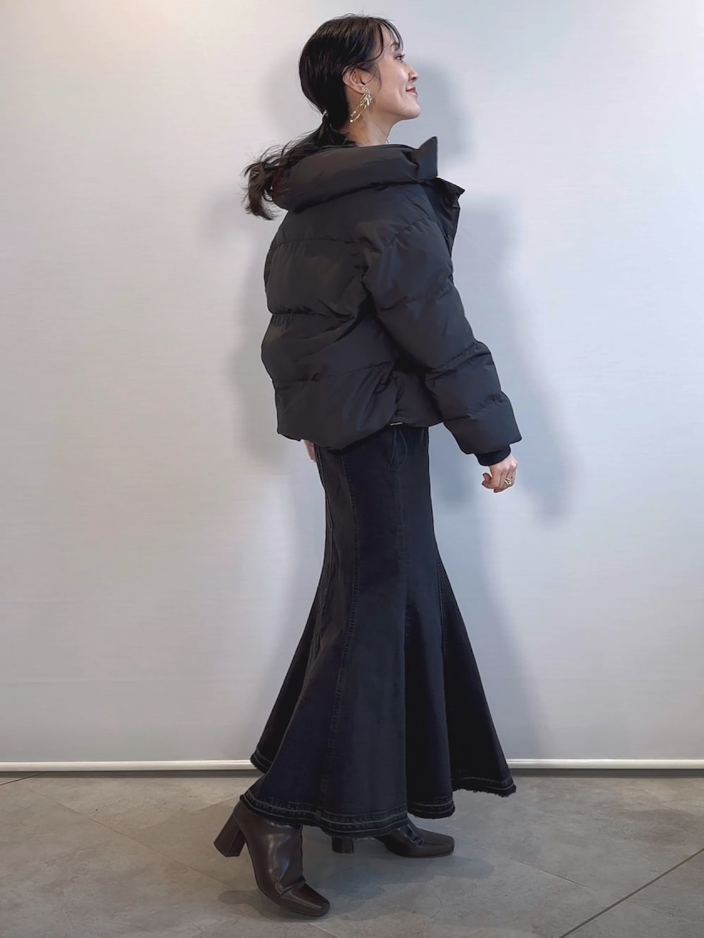 ブラウン系のブーツ、ブラック系のデニムスカート、ブラック系のダウンジャケット/コートを着用したレディースの冬コーディネートの2枚目の写真