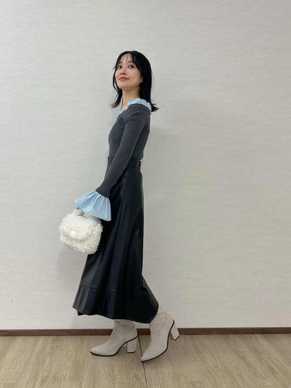 ホワイト系のハンドバッグ、グレー系のブーツ、グレー系のニット/セーターを着用したレディースの冬コーディネートの2枚目の写真