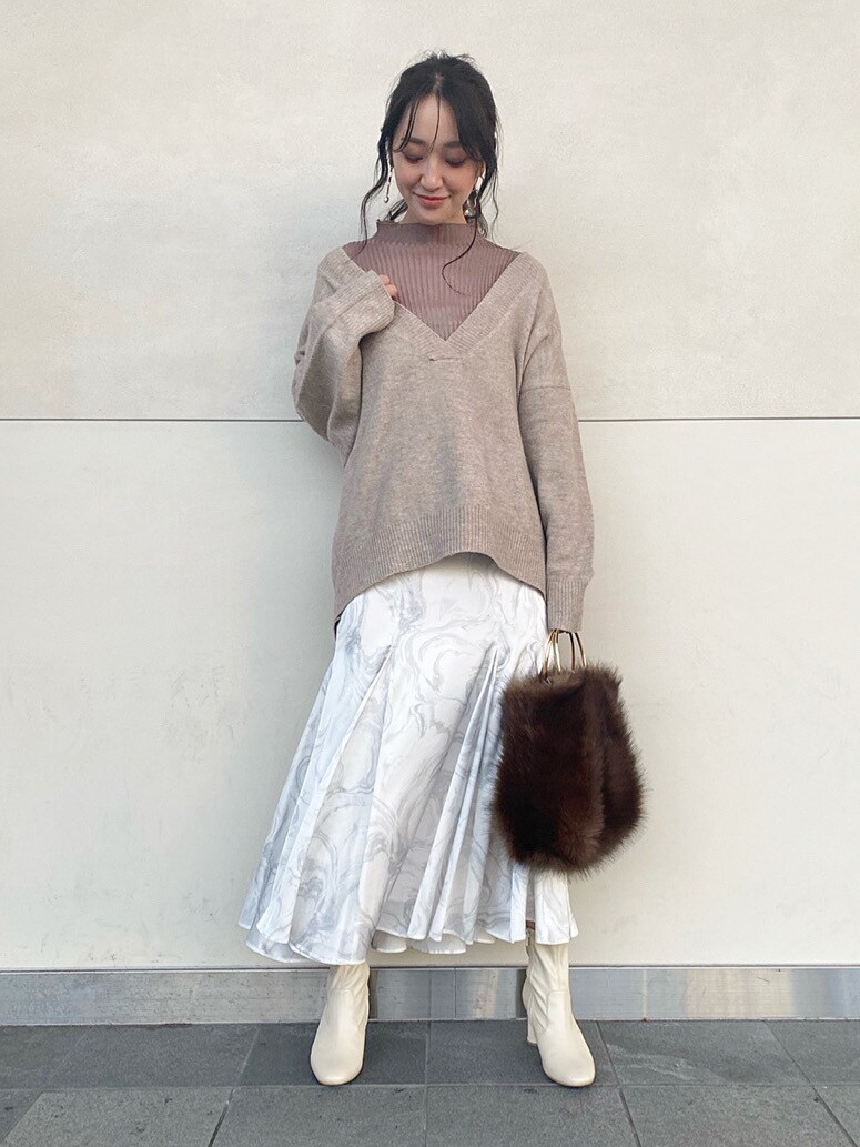ホワイト系のブーツ、ホワイト系のスカート、ベージュ系のニット/セーターを着用したレディースの冬コーディネートの2枚目の写真