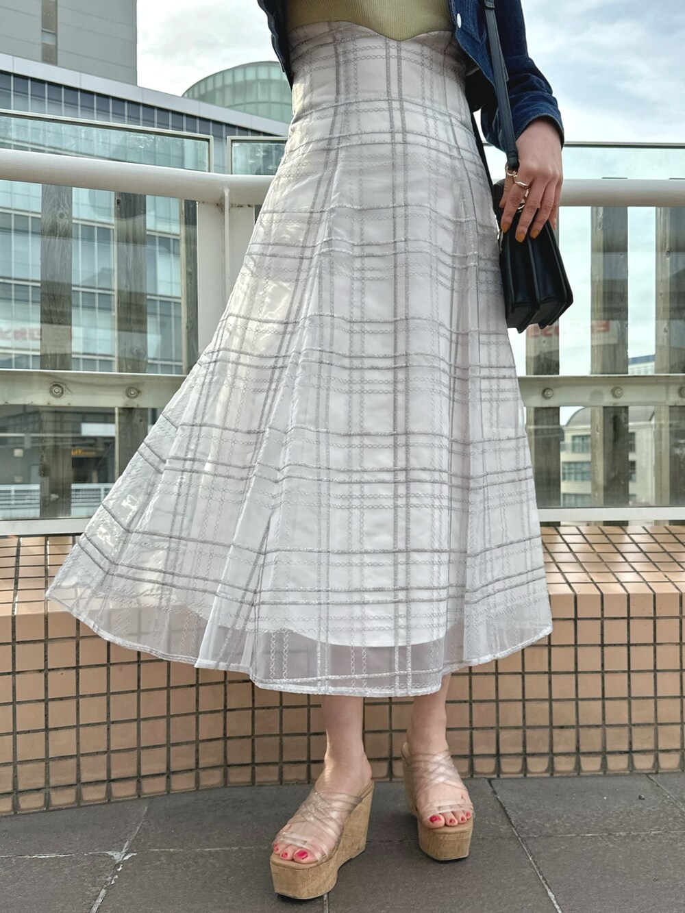 ホワイト系のハンドバッグ、グリーン系のワンピース、ブルー系のデニムジャケットを着用したレディースの春コーディネートの8枚目の写真