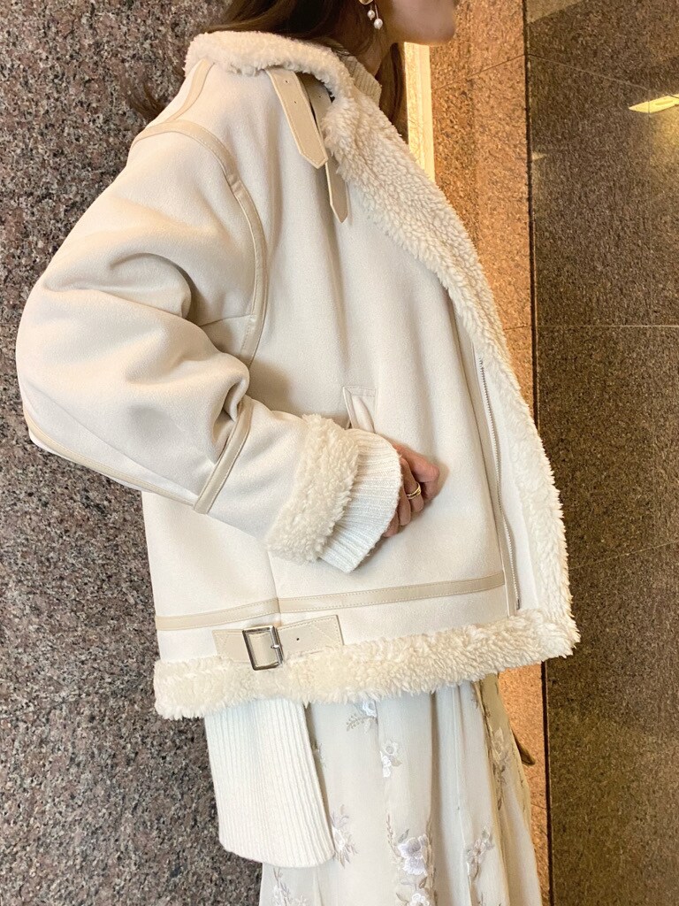 ベージュ系のクラッチバッグ、ホワイト系のムートンコート、ホワイト系のニット/セーターを着用したレディースの秋コーディネートの5枚目の写真