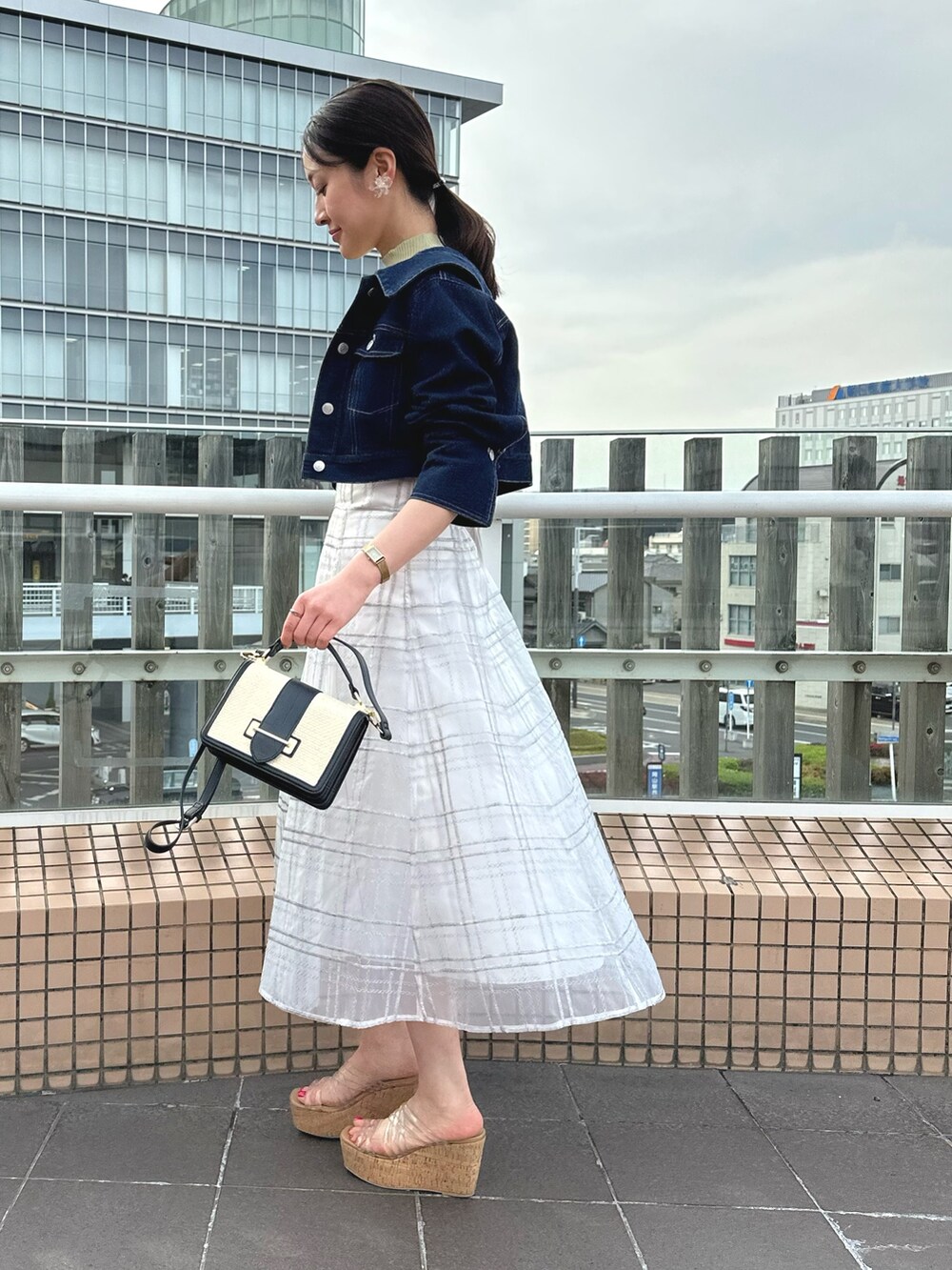 ホワイト系のハンドバッグ、グリーン系のワンピース、ブルー系のデニムジャケットを着用したレディースの春コーディネートの3枚目の写真