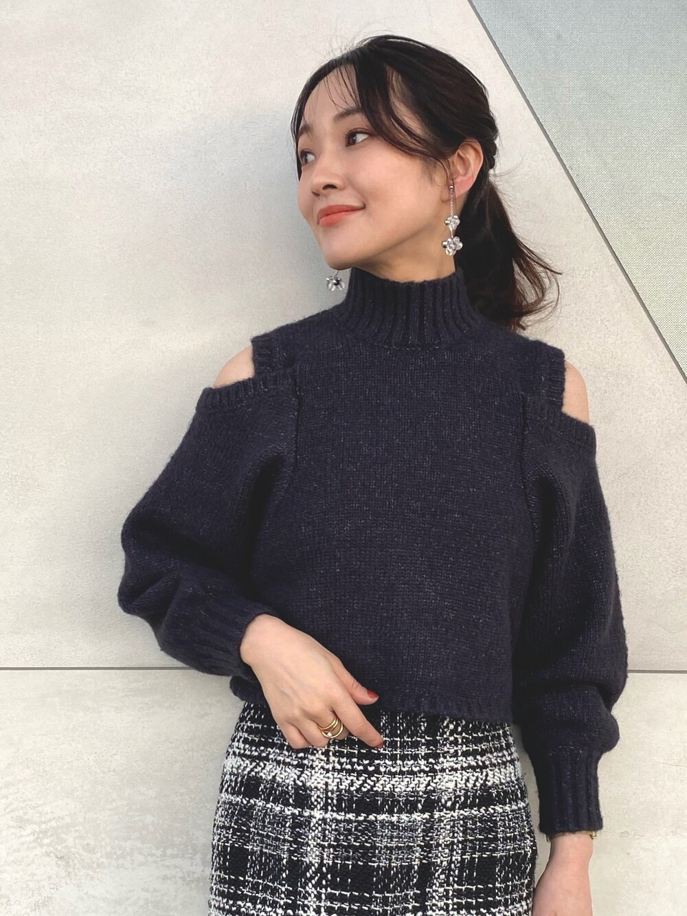 グレー系のニット/セーター、ブラック系のスカート、ブラック系のブーツを着用したレディースの秋コーディネートの4枚目の写真