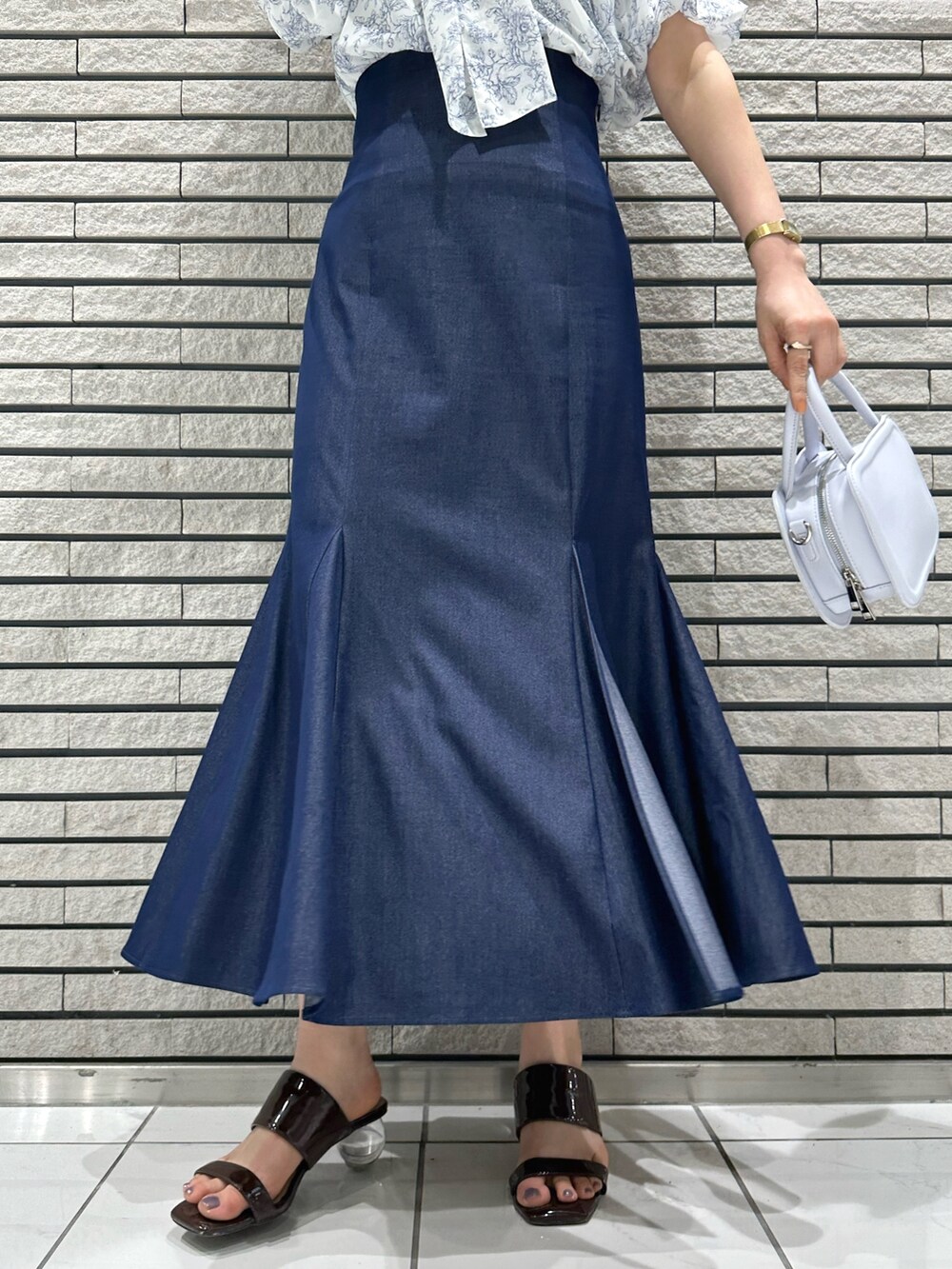 ブルー系のハンドバッグ、ブルー系のスカート、ブルー系のシャツ/ブラウスを着用したレディースの夏コーディネートの8枚目の写真