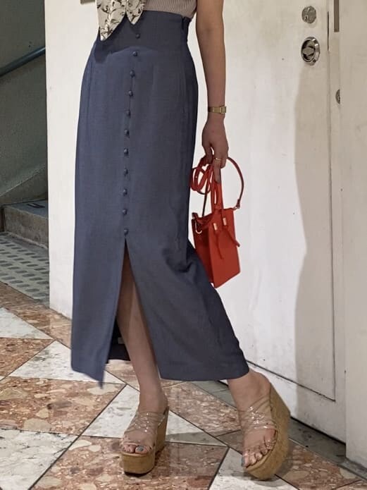 レッド系のハンドバッグ、その他のサンダル、ブルー系のスカートを着用したレディースの夏コーディネートの3枚目の写真