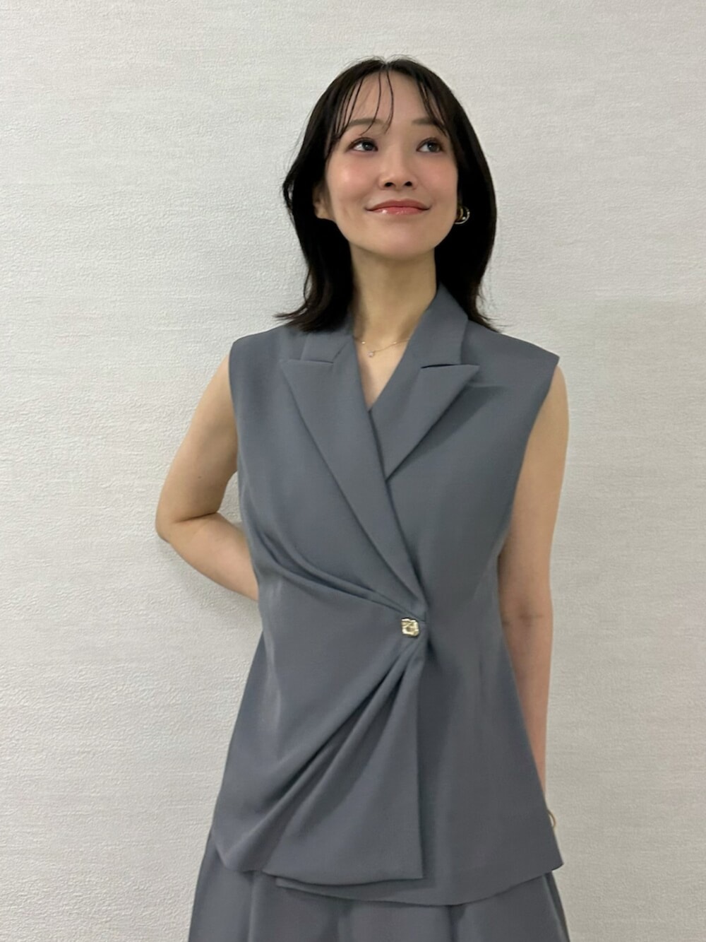 ブラック系のチューブトップ、ピンク系のショルダーバッグ、グレー系のベストを着用したレディースの春コーディネートの6枚目の写真