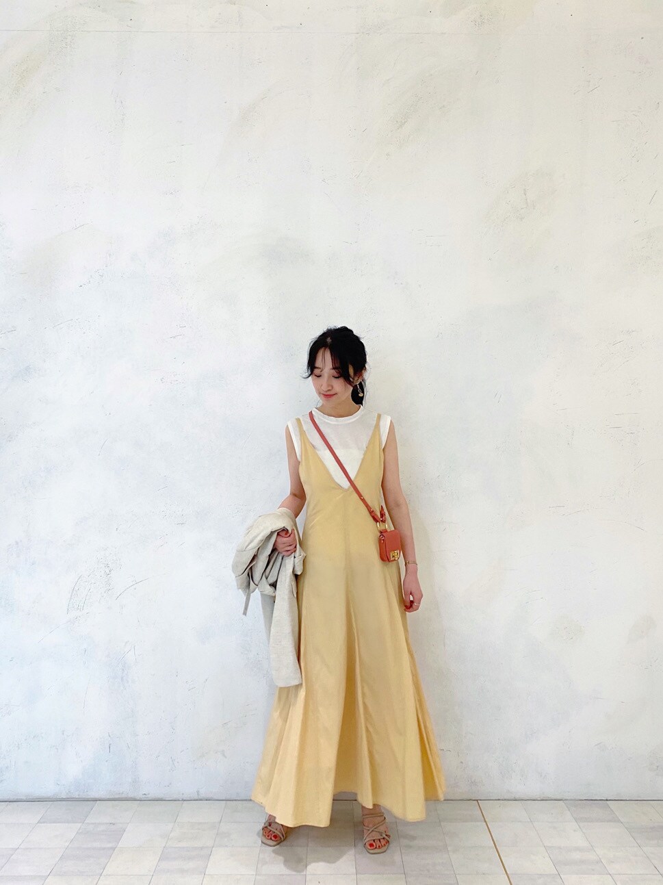 イエロー系のワンピース、ベージュ系のニット/セーター、ホワイト系のテーラードジャケットを着用したレディースの春コーディネートの2枚目の写真