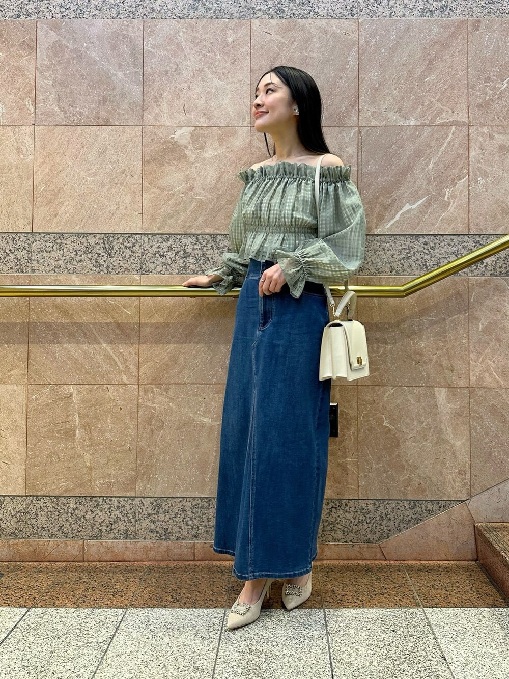 グリーン系のシャツ/ブラウス、ブルー系のデニムスカート、ベージュ系のパンプスを着用したレディースの冬コーディネートの2枚目の写真