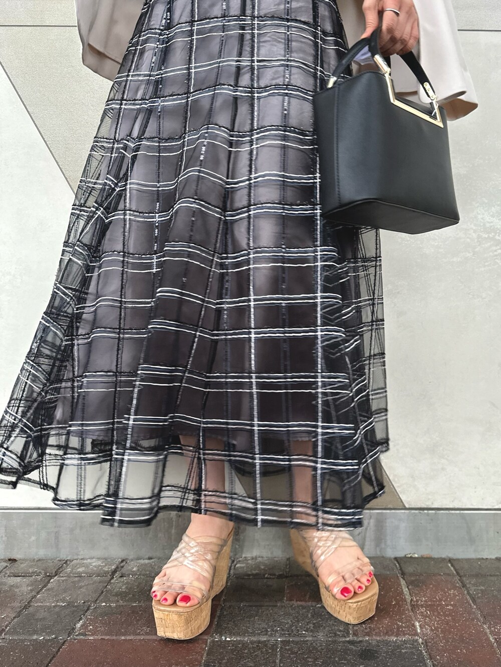 ブラック系のハンドバッグ、ブラック系のスカート、その他のサンダルを着用したレディースの春コーディネートの8枚目の写真