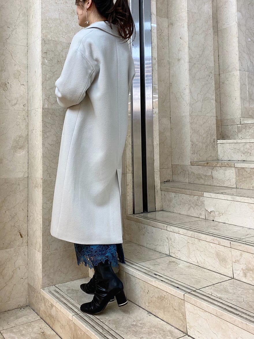 グリーン系のチェスターコート、ブルー系のスカート、ブラック系のその他シューズを着用したレディースの秋コーディネートの3枚目の写真