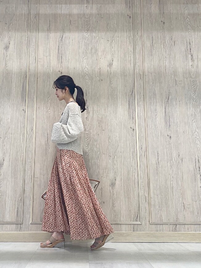 ブラウン系のトートバッグ、ベージュ系のカーディガン/ボレロ、オレンジ系のワンピースを着用したレディースの春コーディネートの2枚目の写真