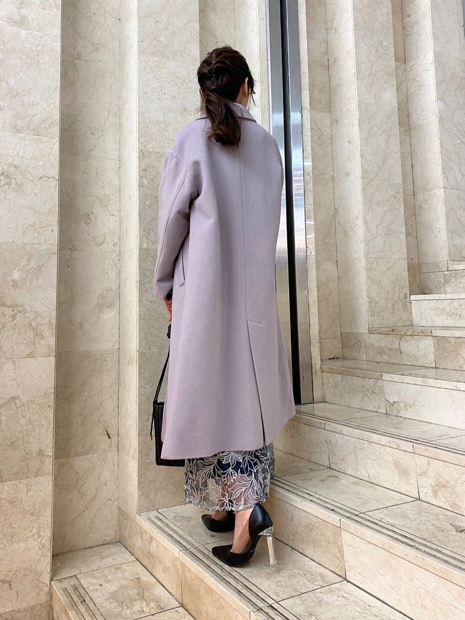 ピンク系のチェスターコート、ブラック系のパンプス、ブラック系のハンドバッグを着用したレディースの秋コーディネートの2枚目の写真