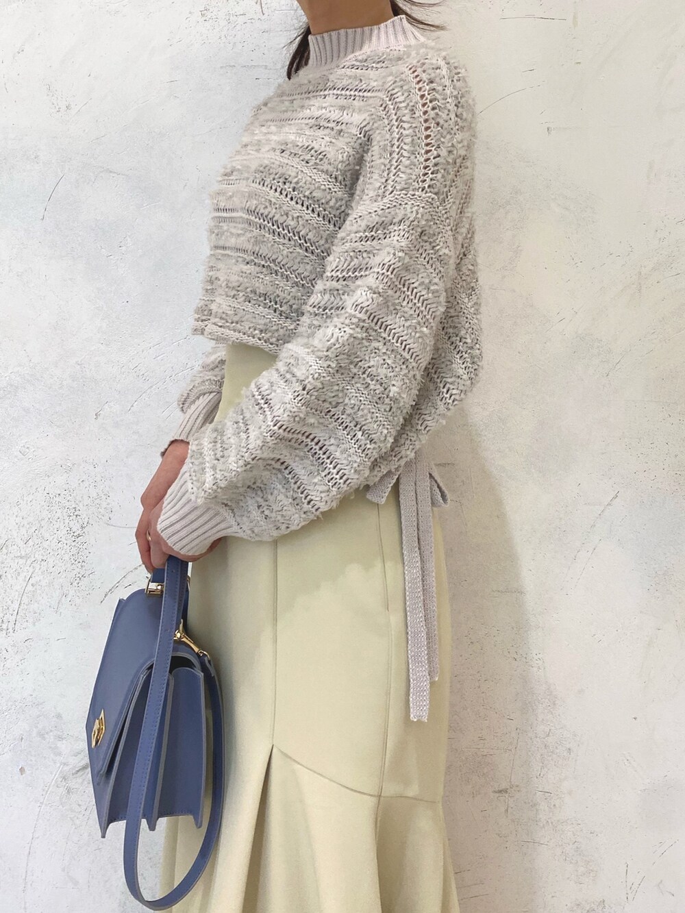 ホワイト系のローファー、イエロー系のスカート、ブルー系のハンドバッグを着用したレディースの冬コーディネートの6枚目の写真